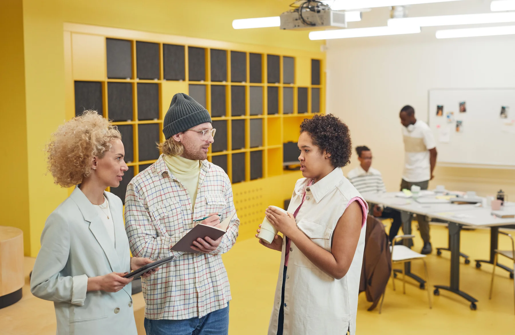Colleagues talking in a yellow-walled shared workspace